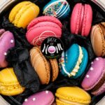 Assorted handcrafted French macarons in a clear gift box featuring vibrant colours, premium fillings and Box of Nom branding.