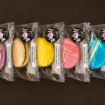 A selection of individually wrapped handcrafted French macarons in assorted flavours, branded by Box of Nom.