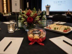 Elegant corporate conference table featuring a Box of Nom macaron gift box, gourmet catering, floral centrepiece and premium business event décor.