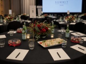 Corporate event table featuring Box of Nom macaron gift boxes, gourmet catering, elegant floral centrepieces and professional conference décor.